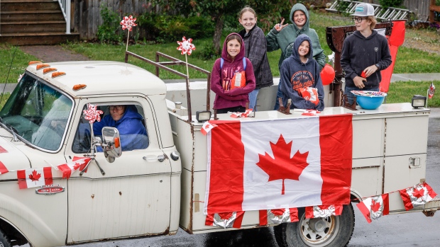Teenagers ride in a vintage truck in a parade during rainy Canada Day celebrations in Cremona, Alta., Monday, July 1, 2024.THE CANADIAN PRESS/Jeff McIntosh