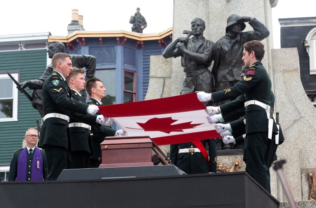 Pallbearers, members of the Royal Newfoundland Regiment, remove the Canadian Flag as an unknown First World War Newfoundland and Labrador soldier is interned at the National War Memorial in St. John's Monday, July 1, 2024. THE CANADIAN PRESS/Paul Daly