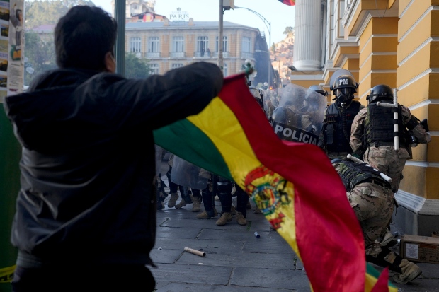 A supporter of President Luis Arce waves a Bolivian flag as soldiers flee from Plaza Murillo, after a failed coup attempt, in La Paz, Bolivia, Wednesday, June 26, 2024. (AP Photo/Juan Karita)
