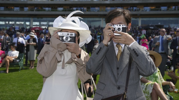 Two racegoers photograph the photographer as they watch the racing in the public enclosure on the second day of the Royal Ascot horse race meeting at Ascot, England, Wednesday, June 19, 2024. (AP Photo/Kin Cheung)